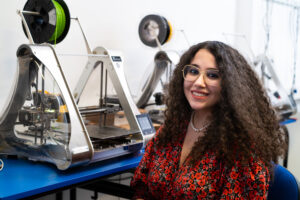 Kobieta siedząca obok drukarki 3D