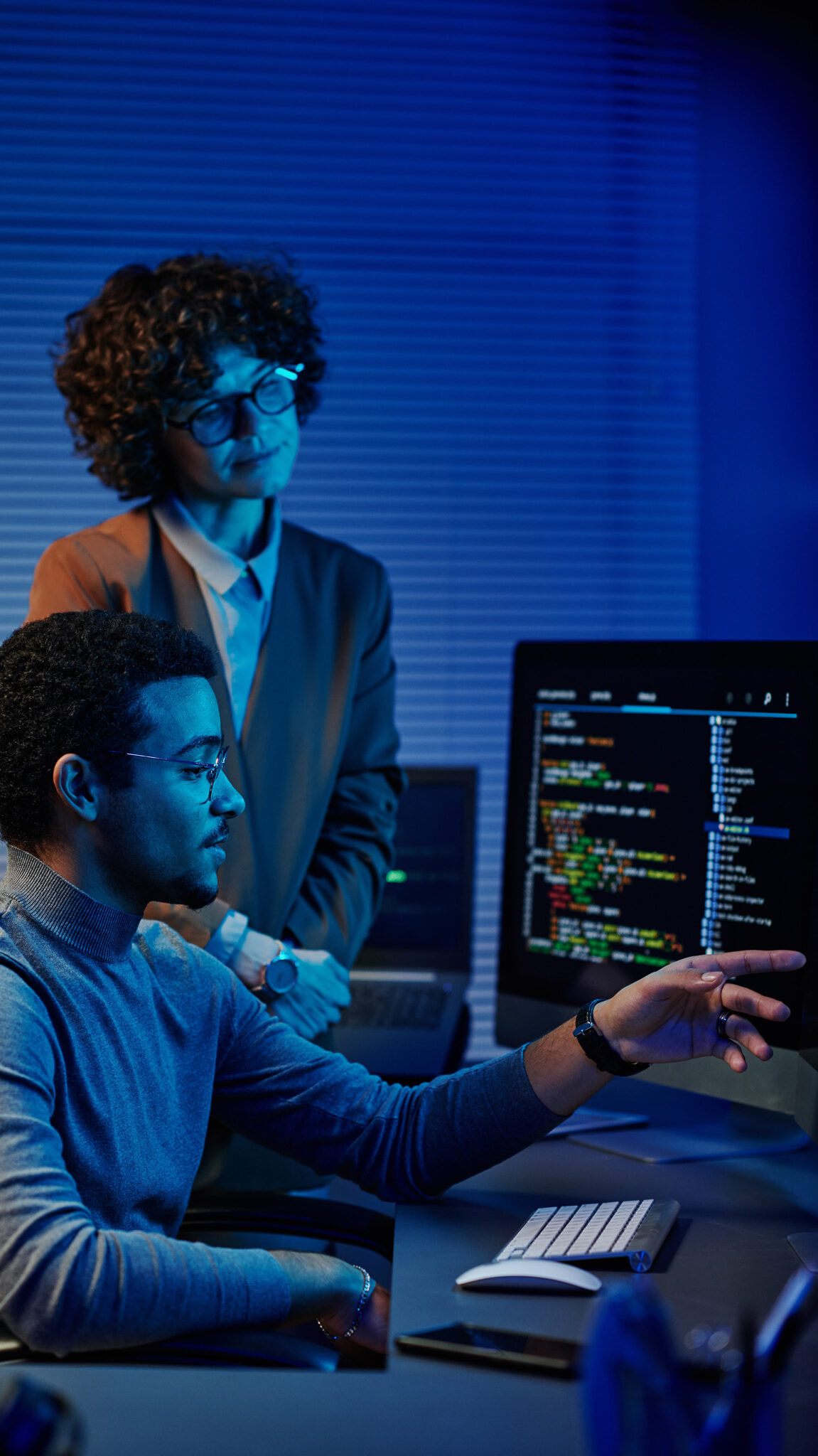 Inżynier danych analizujący kod na ekranie w obecności współpracowniczki – scena pracy zespołowej nad projektem Big Data.