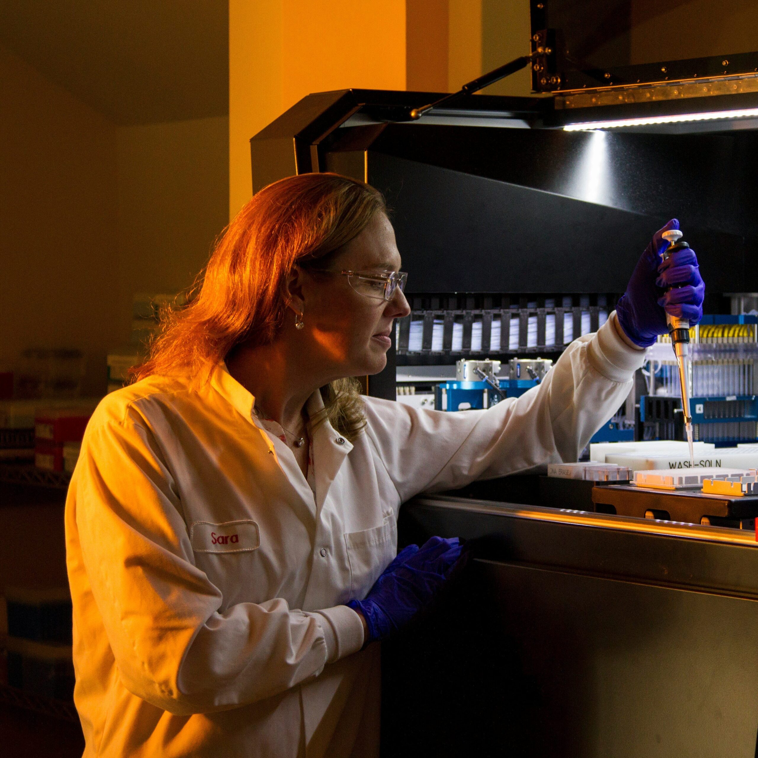 Naukowczyni w laboratorium pracująca przy maszynie badawczej.