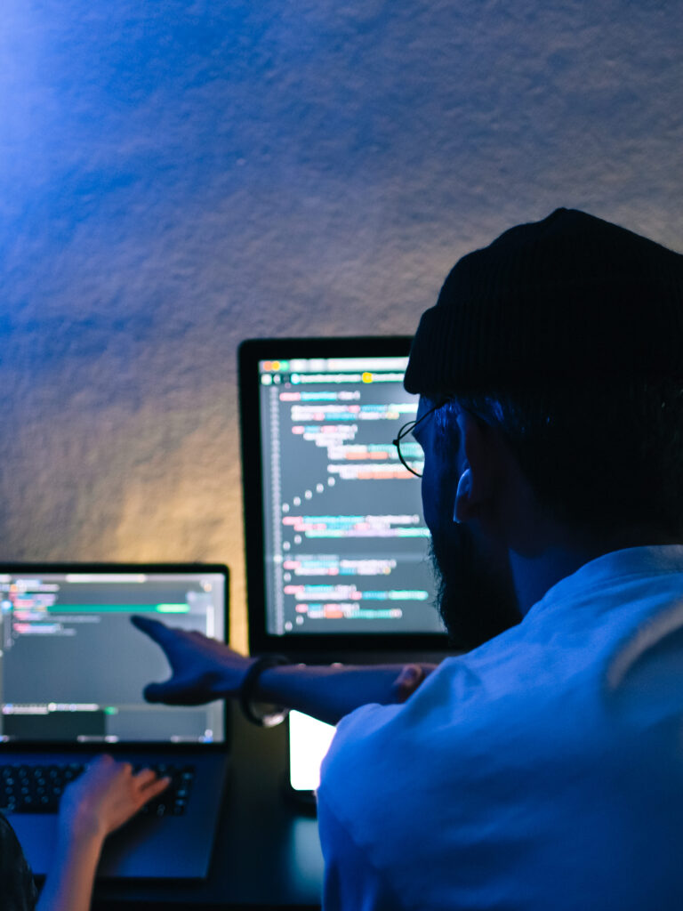 Programista wskazujący na kod an laptopie