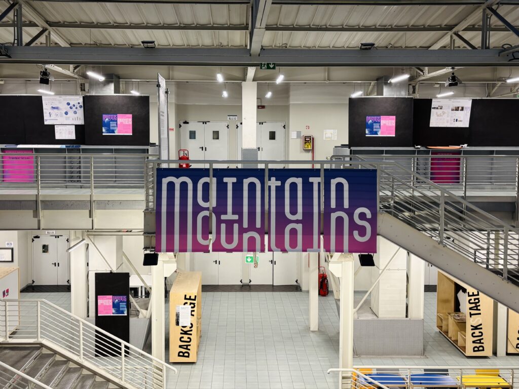 Dokumentacja wystawy „Maintain Mountains – Design for Post-Event Mountain Resilience” na Politecnico di Milano: plansze projektowe „The Vertical Atlas”, model topograficzny z warstwowymi poziomicami oraz przestrzeń ekspozycyjna z dużymi banerami i instalacją w industrialnym wnętrzu kampusu.