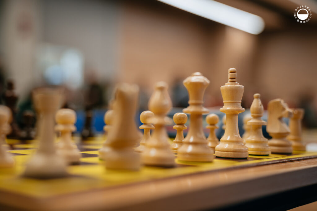 Sędzia główny Mateusz Bronowicki przemawia na scenie na tle grafiki z szachami.