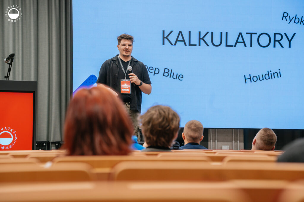 Prelegent przemawia na scenie podczas wydarzenia w auli PJATK, slajd o kalkulatorach szachowych na ekranie.