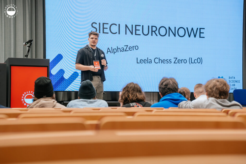 Prelegent przemawia na scenie podczas wydarzenia w auli PJATK