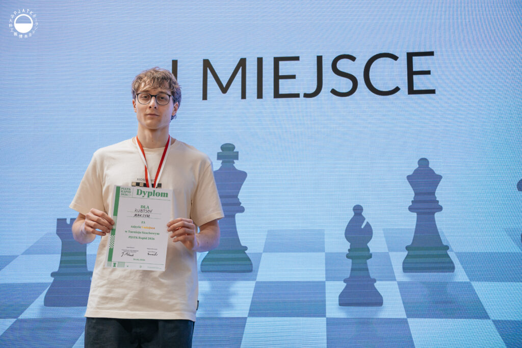 Zwycięzcy turnieju szachowego stoją na scenie z medalami i dyplomami.