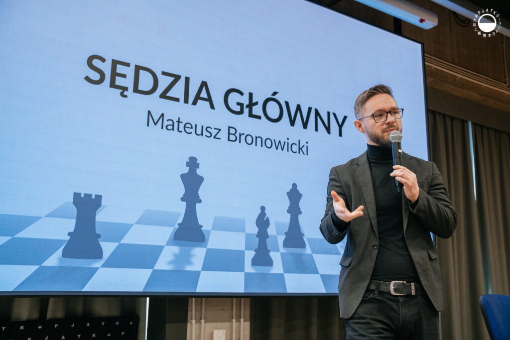 Mężczyzna w garniturze mówi do mikrofonu podczas prezentacji w auli.