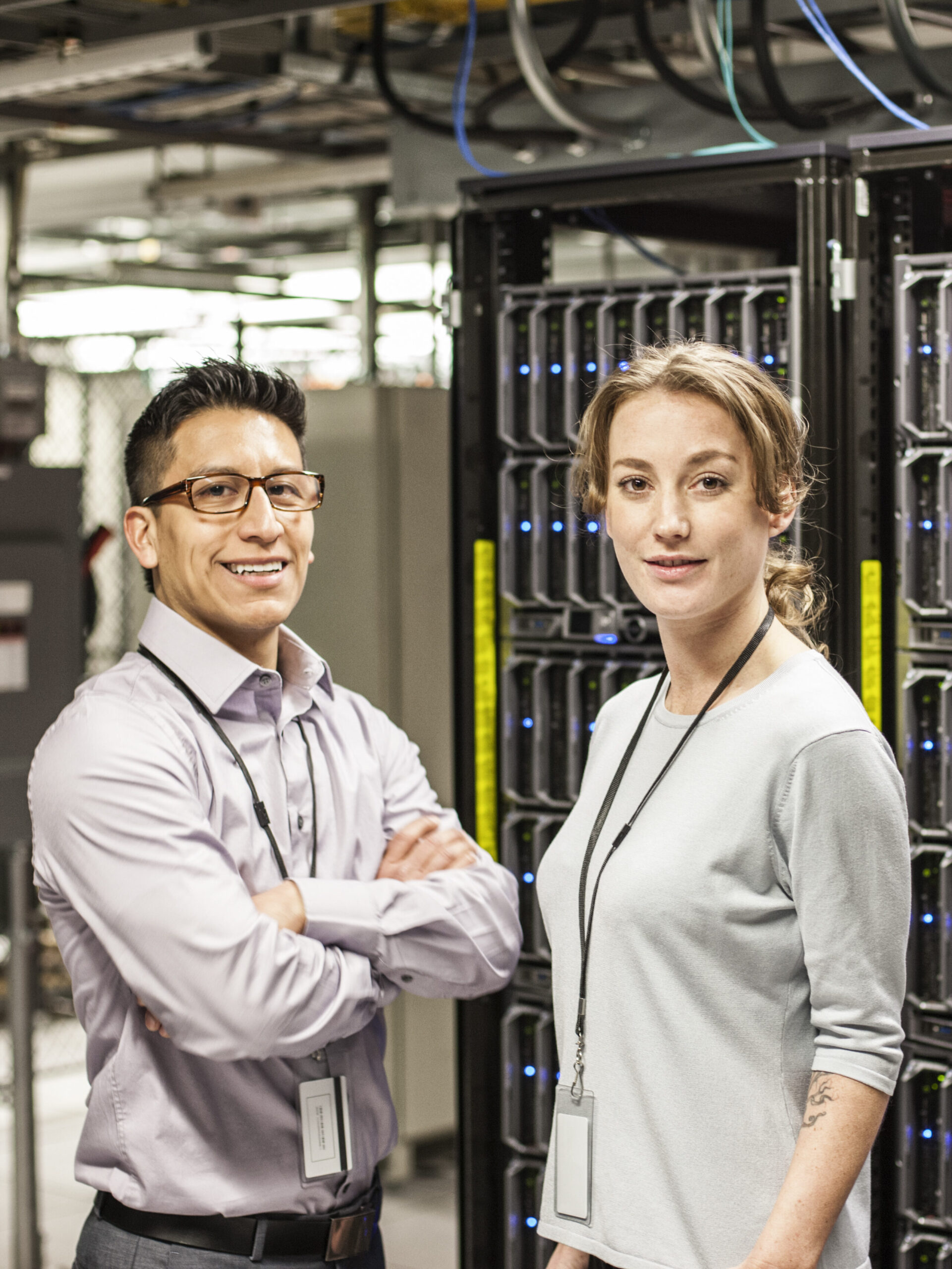 Caucasian man and woman technicians in a large computer server farm.