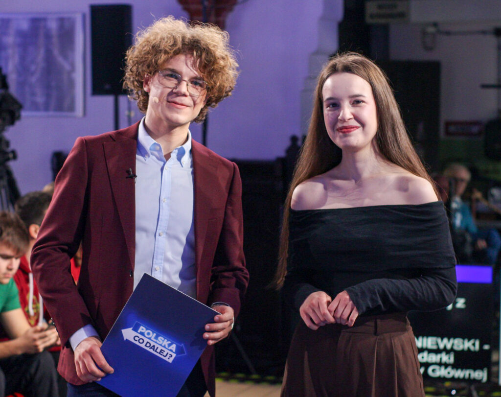 (prowadzący stoją) Prowadzący program „Polska. Co dalej?” stoją w studiu, trzymając materiały do debaty.