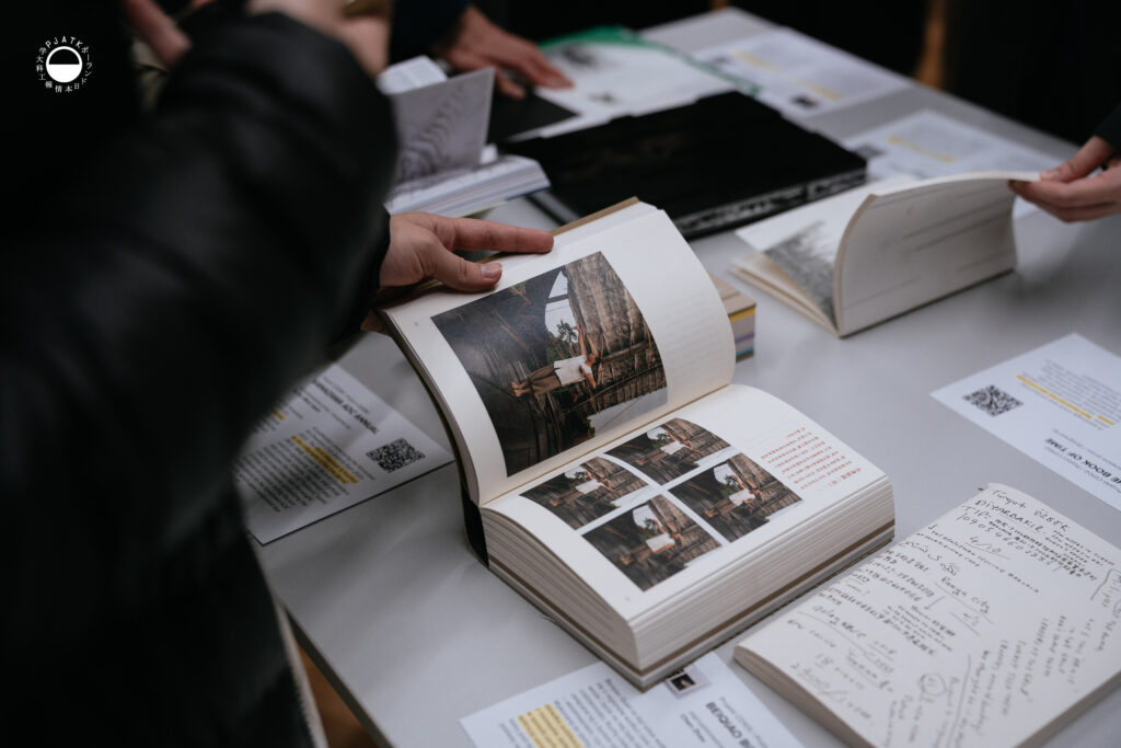 Zbliżenie na otwartą książkę z projektami graficznymi oglądaną przez uczestnika.