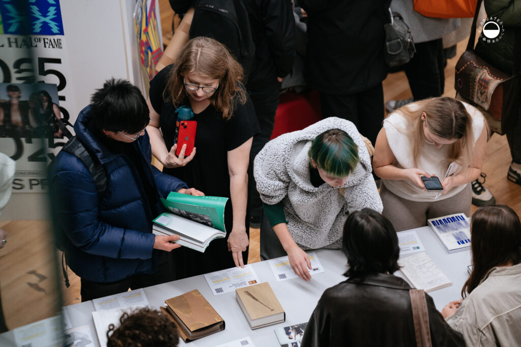 Uczestnicy pochylają się nad publikacjami i opisami projektów, analizując szczegóły prac.