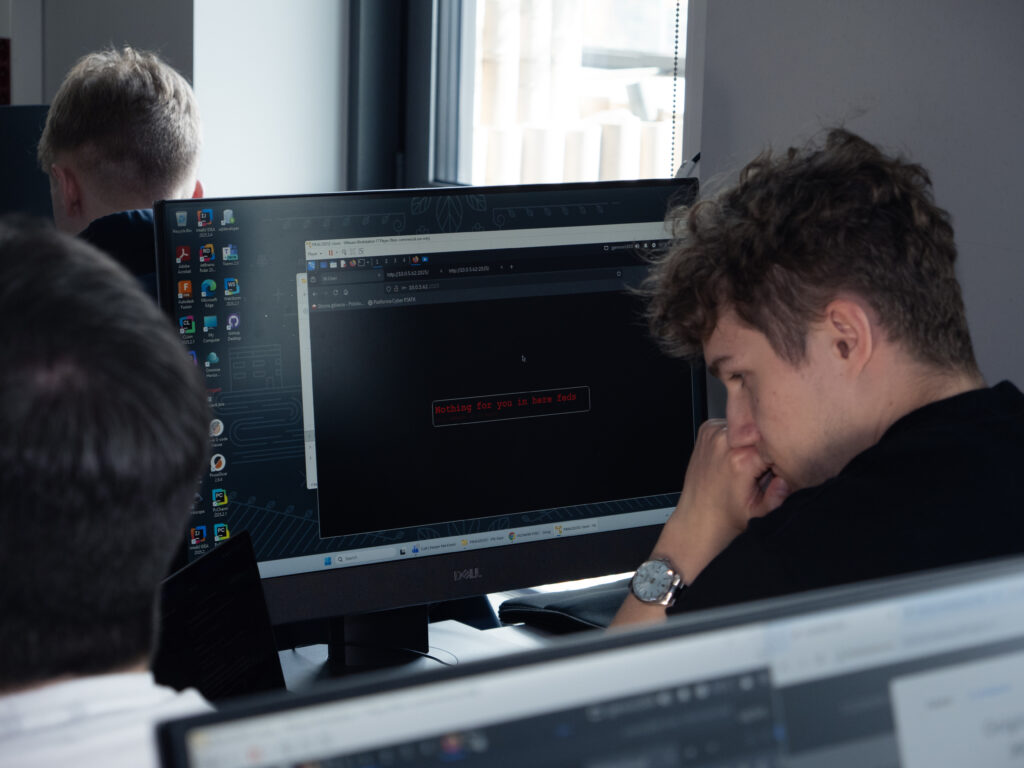 A student is analyzing code on a monitor in the computer lab, focused on a cybersecurity-related task.