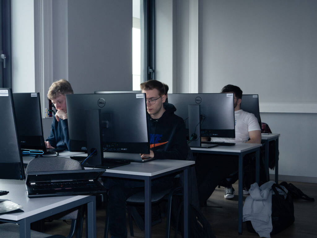 Students are working on computers in the classroom, completing practical assignments related to cybersecurity.