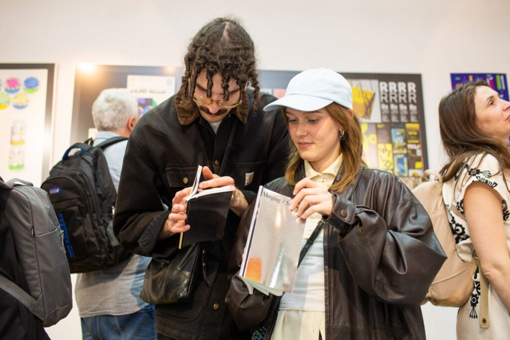 Dwie osoby oglądają i porównują publikacje typograficzne podczas wydarzenia.