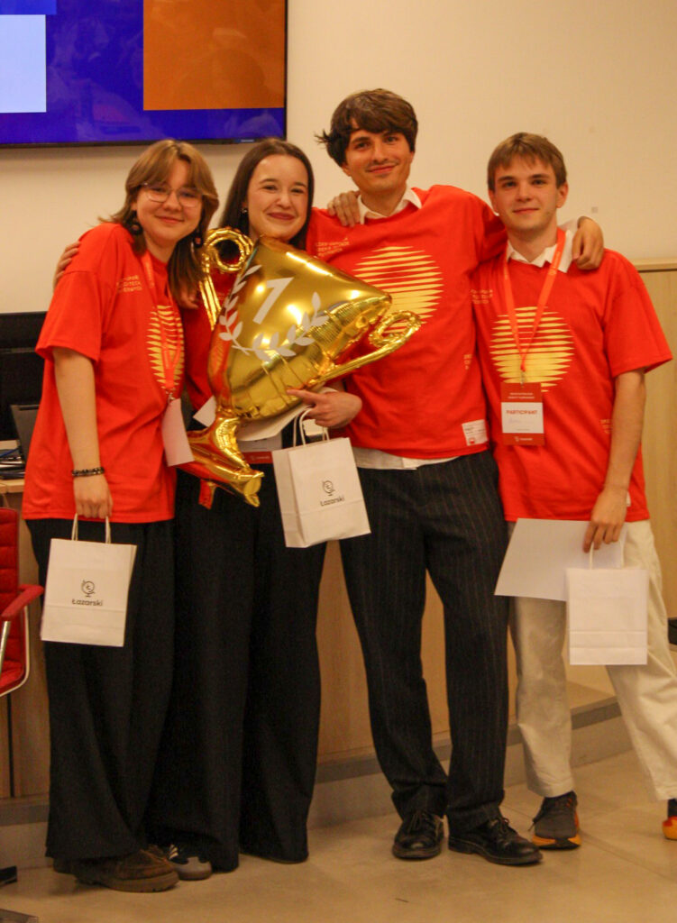 Zdjęcie członków Kaizen Debate Club w uczelnianych tshirtach z balonem w kształcie pucharu